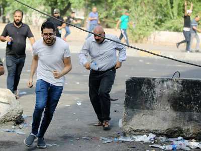 Des Irakiens courent pour échapper aux gaz lacrymogène tirés par la police antiémeutes à Bagdad le 3 octobre 2019 où se déroulent des manifestations contre la corruption et le chômage - AHMAD AL-RUBAYE [AFP]